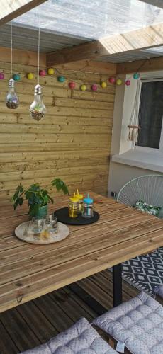 une table en bois avec une plante et des billes sur un mur dans l'établissement Le Spot Blériot-Plage gîte de groupe proche mer, à Sangatte