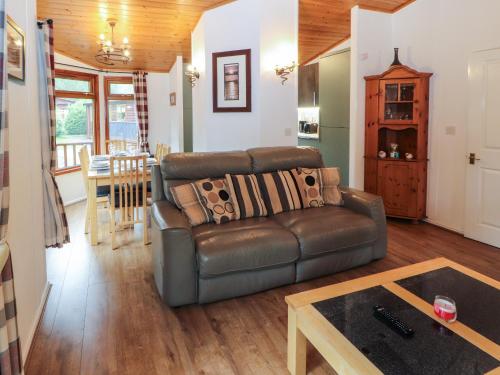 a living room with a leather couch and a table at Langdale Lodge 15 in Windermere