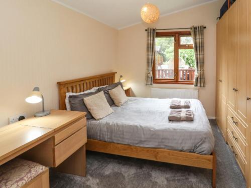a bedroom with a bed and a desk and a window at Langdale Lodge 15 in Windermere