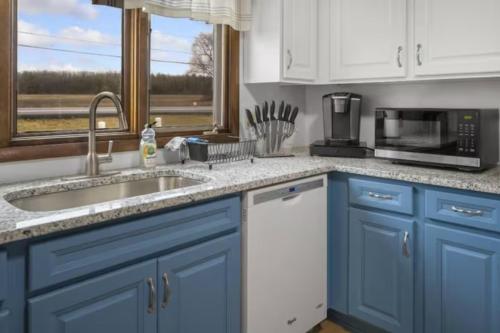 a kitchen with blue cabinets and a sink and a microwave at Cayuga bungalow on lake—sleeps 13—outdoor firepit in Lansing