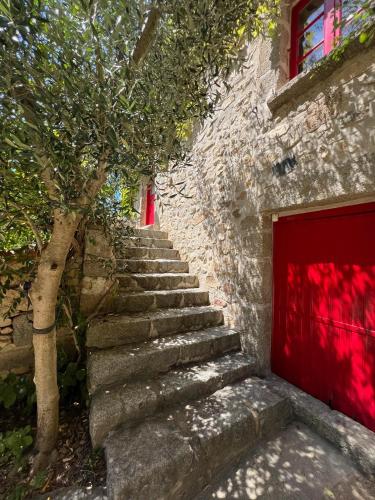a stone building with a red door and stairs at Mas Lo Faix in Saint-Laurent-de-Cerdans