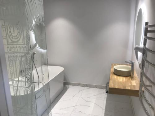 een witte badkamer met een bad en een wastafel bij Logis Hôtel Restaurant La Vraine in Gironcourt-sur-Vraine
