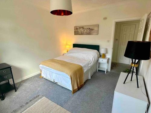 a bedroom with a bed and a table with a lamp at Spindrift, Spacious bungalow near beach in Hamworthy