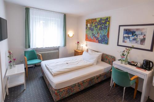 a hotel room with a bed and a desk and chairs at Alleehaus in Freiburg im Breisgau