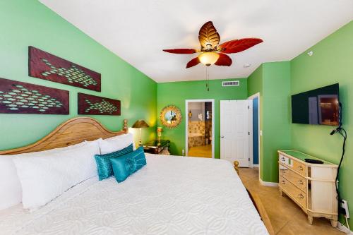 Tarpon Watch في كي ويست: غرفة نوم بجدران خضراء وسرير مع مروحة سقف