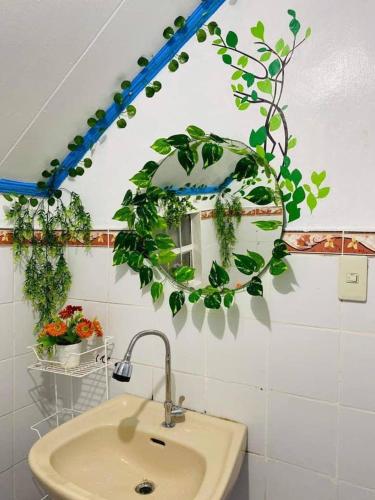 a bathroom with a sink and a mirror with plants at Paula's Tagaytay Transient House in Tagaytay
