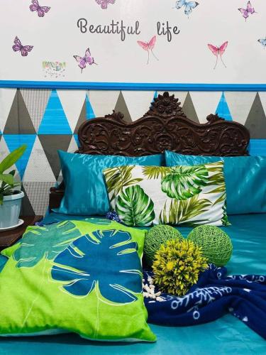 a bed with blue and green pillows and plants on it at Tagaytay Budget House in Tagaytay