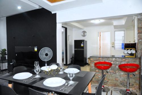 Maison Dos 3 bedroom, with 200mbps internet speed, netflix and aircon في أنتيبولو: غرفة طعام مع طاولة سوداء وكراسي حمراء
