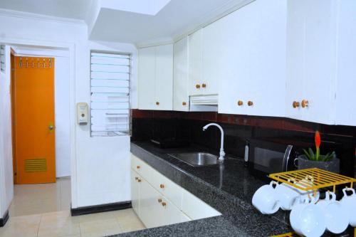 uma cozinha com armários brancos e um lavatório em Maison Dos 3 bedroom, with 200mbps internet speed, netflix and aircon em Antipolo
