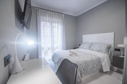 biała sypialnia z łóżkiem, stołem i oknem w obiekcie Gran Apartamento 6 SUITES Bilbao Center w mieście Bilbao