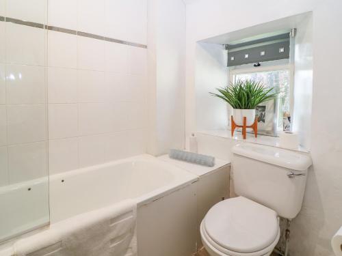 a white bathroom with a toilet and a bath tub at Primrose Cottage Stow in Stow on the Wold