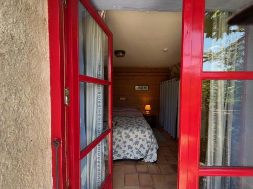 a red door leading to a bedroom with a bed at Mas Lo Faix in Saint-Laurent-de-Cerdans