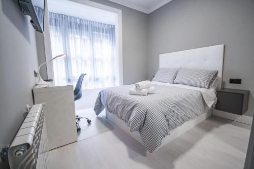 Biała sypialnia z łóżkiem z pluszowym misiem w obiekcie Gran Apartamento 6 SUITES Bilbao Center w mieście Bilbao