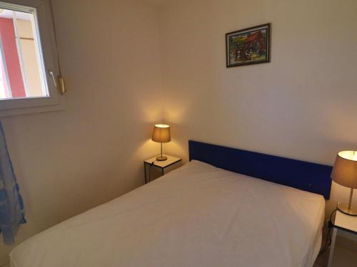 une chambre avec un lit avec une tête de lit bleue et deux lampes dans l'établissement 2 pièces cabine, WIFI, terrasse 6m², dernier étage à Sète - FR-1-472A-230, à Sète