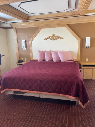 a hotel room with a large bed with pink pillows at Budget Inn and Suites Corpus Christi in Corpus Christi