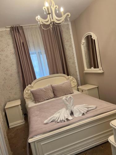 a bedroom with a white bed with a chandelier at Pensiunea Baroc in Braşov
