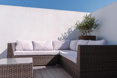 a wicker couch sitting on a patio at Retiro da Atafona Beach Pool House White in Monte