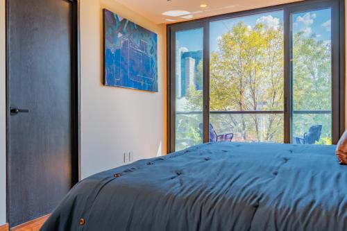 sypialnia z niebieskim łóżkiem i dużym oknem w obiekcie Asra w mieście Meksyk