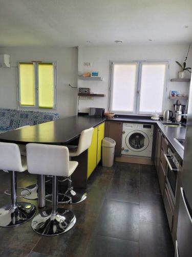 une cuisine avec un comptoir noir et des armoires jaunes dans l'établissement Cabanès des Aresquiers, à Frontignan