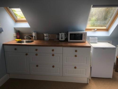 uma cozinha com um balcão com um micro-ondas e um lavatório em Porthcawl, Nr Sea & Centre. Private guest suite. em Porthcawl