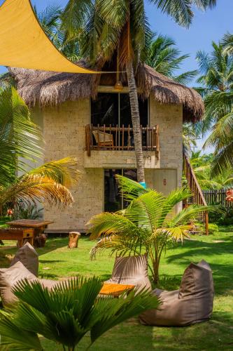 a resort building with a thatch roof and palm trees at Palmarito Beach Hotel in Tierra Bomba