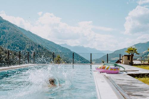 eine Person schwimmt in einem Pool mit einem Schieferboot in der Unterkunft Hotel Bergschlössl in Lüsen