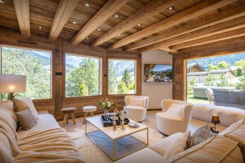 Elle comprend un salon doté d'un mobilier blanc et de grandes fenêtres. dans l'établissement Chalet Tinatha - OVO Network, à La Clusaz
