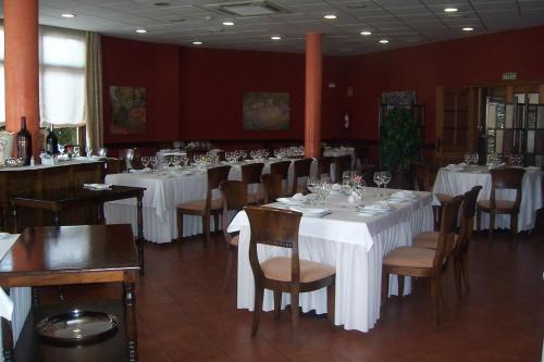 un comedor con mesas y sillas blancas en Hotel Restaurante Los Prados, en Loeches