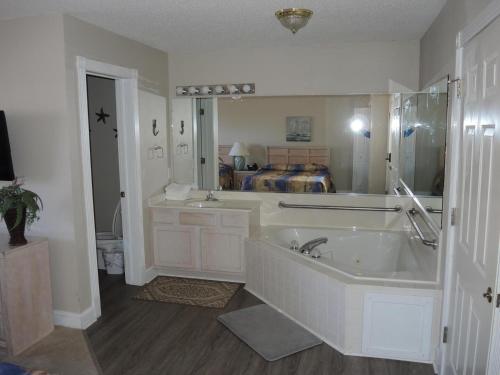 a white bathroom with a tub and a bed at Brunswick Plantation Studio Home 407L with Onsite Golf Course and Pools studio in Calabash