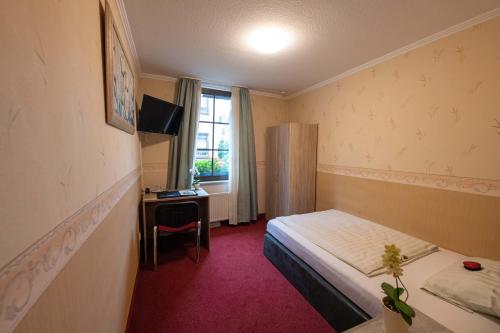 um quarto de hotel com uma cama, uma secretária e uma janela em Hotel Am Rathaus em Menden