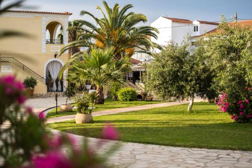 a garden in front of a house with palm trees and flowers at Konstantina Apartments in Kavos