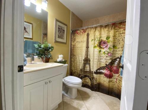 a bathroom with a toilet and a sink and a shower curtain at A Treasure Coast Gem. in Port Saint Lucie