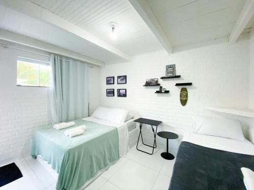 a white room with two beds and a table at Casa do Point in Saquarema