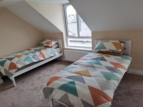 a bedroom with two beds and a window at 3 Riverwalk, Wicklow Town in Wicklow