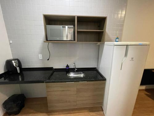 uma pequena cozinha com um lavatório e um micro-ondas em Flat Aconchegante em Sorocaba