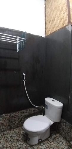 a bathroom with a white toilet in a black wall at Ijen Farmer Homestay in Banyuwangi