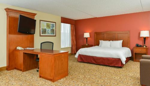 a hotel room with a bed and a desk with a television at Hampton Inn Chicago-Carol Stream in Carol Stream