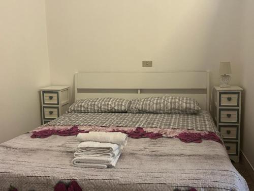 a bedroom with a bed with towels and two night stands at L'angolo della felicità in Marina di Montenero
