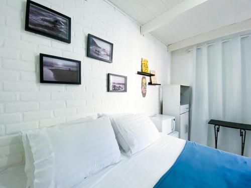 a white bed in a bedroom with pictures on the wall at Casa do Point in Saquarema
