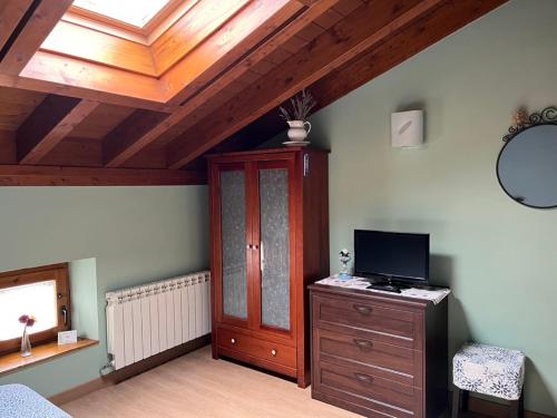 a bedroom with a wooden ceiling and a tv on a dresser at La Cabala de Ibeas in Ibeas de Juarros