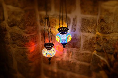 a group of lights hanging from a stone wall at Pure Vida in ‘Akko