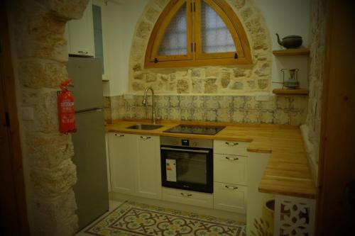 a kitchen with white cabinets and a sink and a window at Pure Vida in ‘Akko