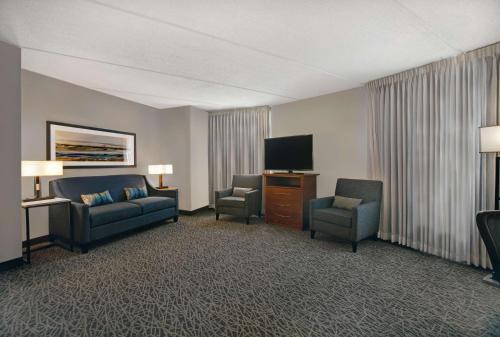 a hotel room with a couch and chairs and a flat screen tv at Homewood Suites by Hilton Chicago-Lincolnshire in Lincolnshire