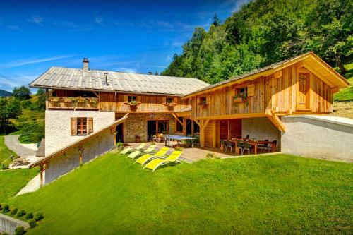 Chalet Ladroit - OVO Network في Les Clefs: منزل خشبي كبير مع كراسي صفراء في الفناء