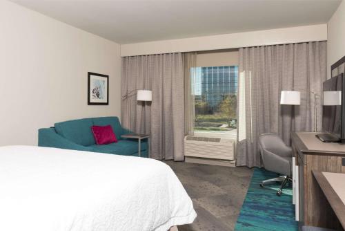 a hotel room with a bed and a couch and a window at Hampton Inn & Suites by Hilton Chicago Schaumburg IL in Schaumburg