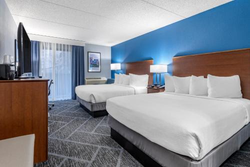 a hotel room with two beds and a blue wall at Best Western Bloomington Edina - Minneapolis in Bloomington