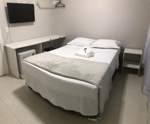 a bedroom with a large white bed and a desk at Grande Hotel in Gurupi