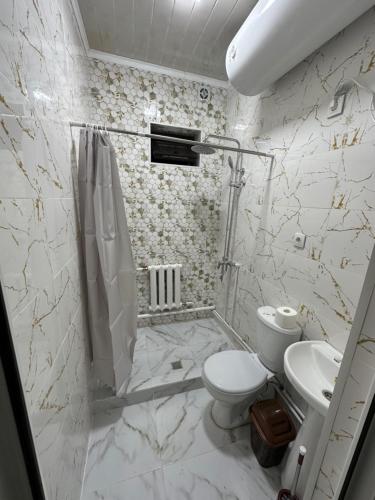 a white bathroom with a toilet and a sink at Kerben House in Naryn