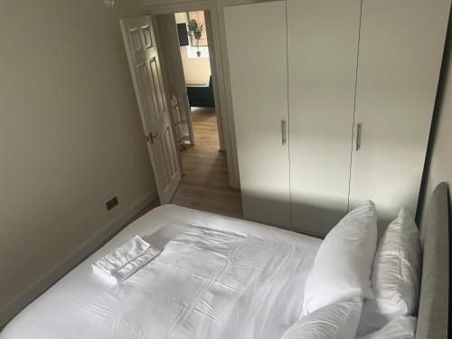 - un lit blanc avec des oreillers blancs dans une chambre dans l'établissement Flat 1 Hobart Lodge, à Hendon