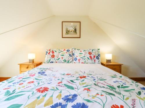a bedroom with a bed with a floral bedspread at The Studio, Horseshoe Cottage in Fulbourn